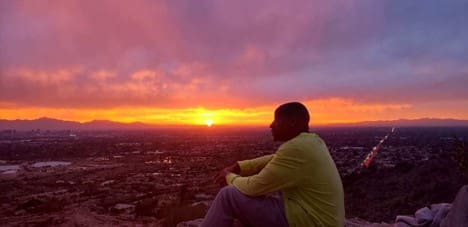 A man sitting on the edge of a mountain while singing